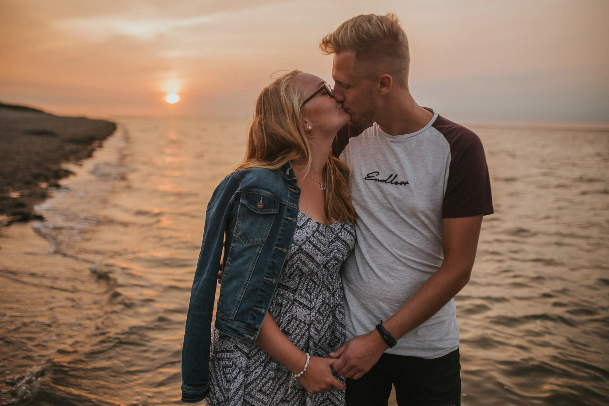 Paar steht bei Sonnenuntergang am Wasser