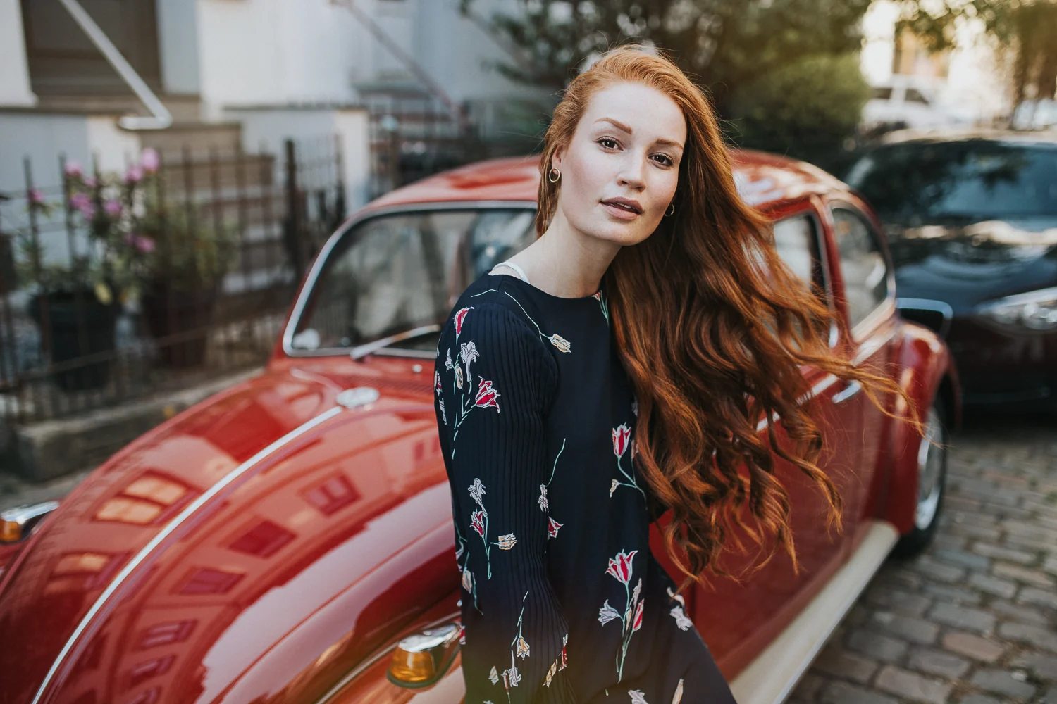 Portrait einer Frau vor einem roten Auto in urbaner Umgebung